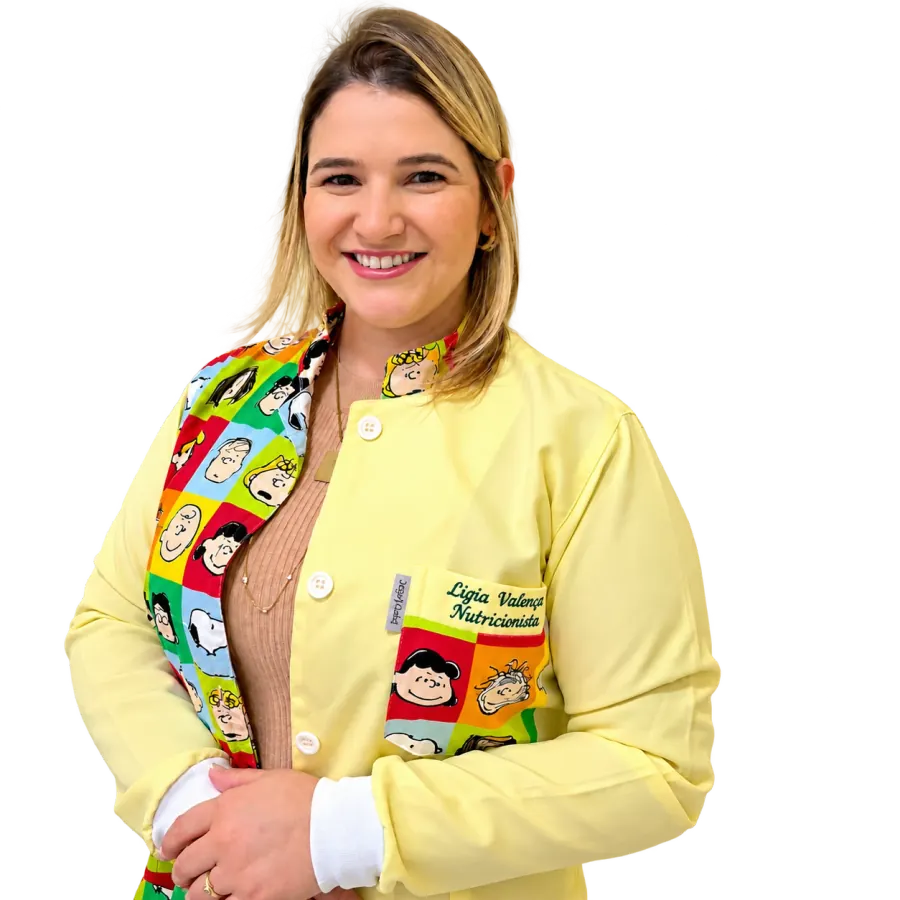 Lígia Valença sorrindo, de jaleco amarelo com estampa da Turma do Snoopy e o bordado Lígia Valença Nutricionista