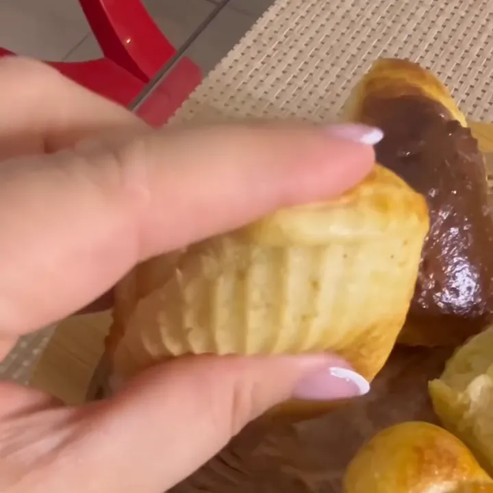 Pãozinho caseiro dourado, recém-saído da forminha, na mão